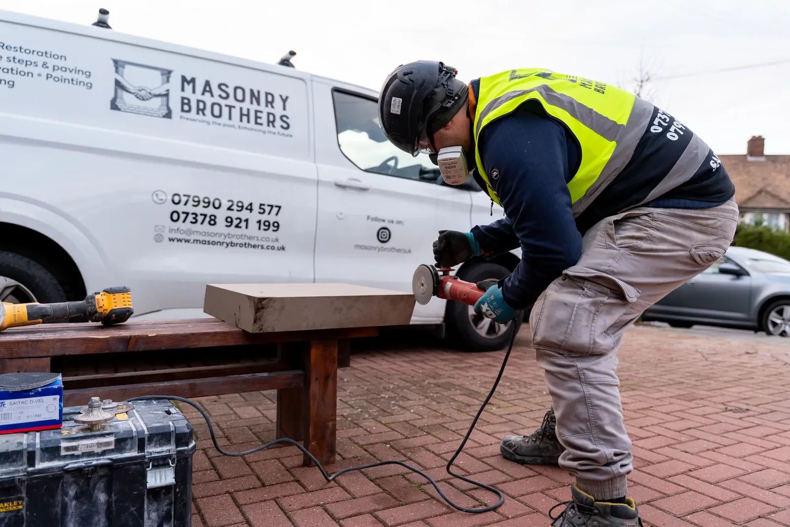 Masonry Brothers worker shaping stone beside the branded company van