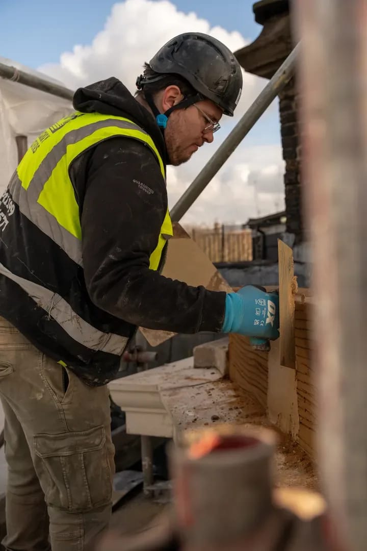 Stone mason cutting and shaping stone on a rooftop