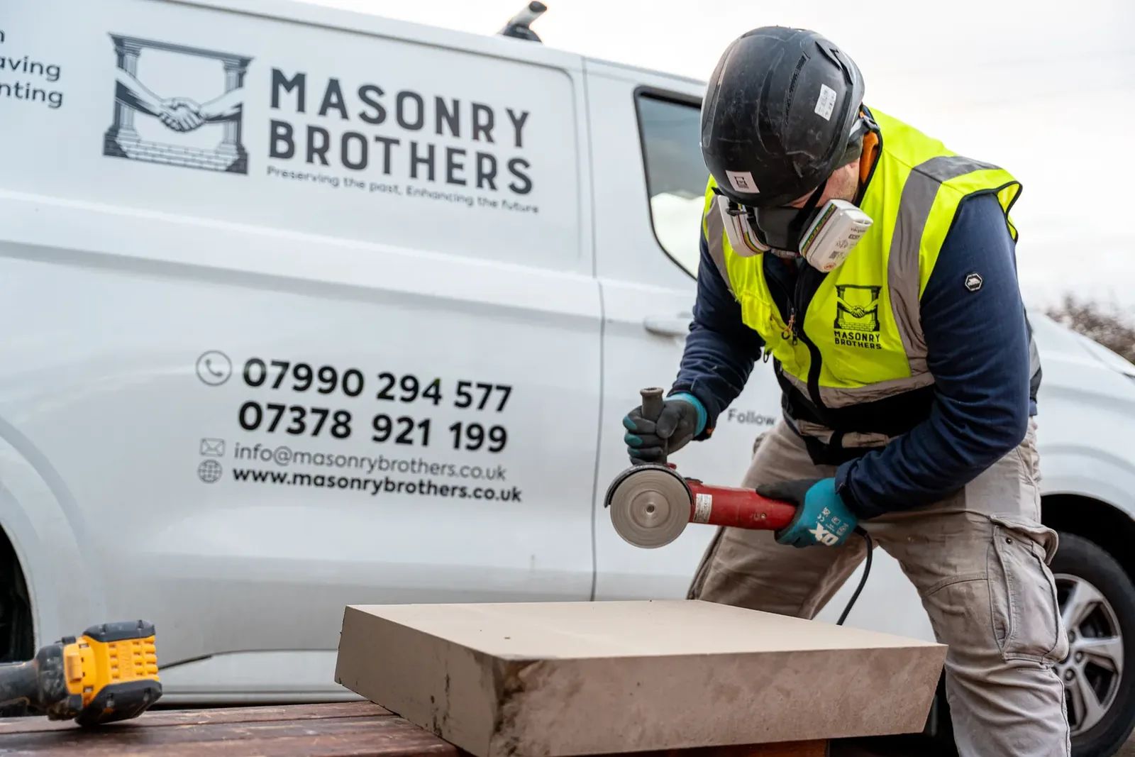 Masonry Brothers craftsman cutting stone by the company van