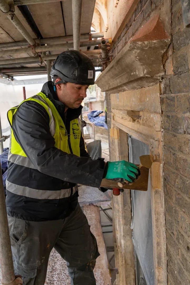 Masonry Brothers worker carefully repointing a heritage window surround